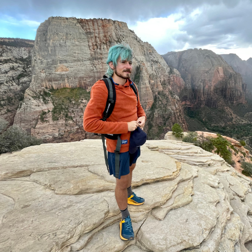 Men's Hiker wearing Orange Rust Highlander Hoodie atop mountain